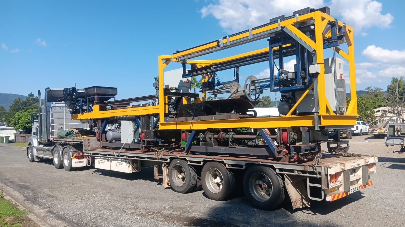 Drop-deck flat-top trailer loaded with industrial machinery