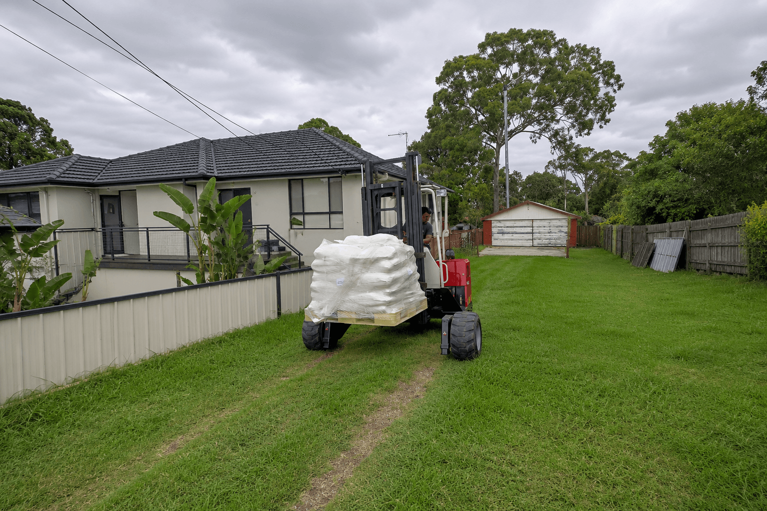Moffett forklift driving palletised freight across a property to place it on site