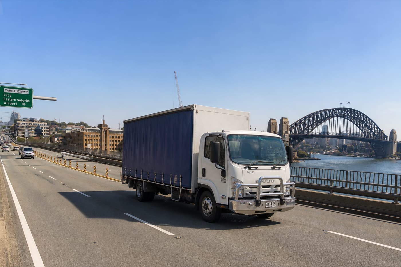 Quick Cargo curtain-side truck on a Sydney expressway with the Harbour Bridge behind